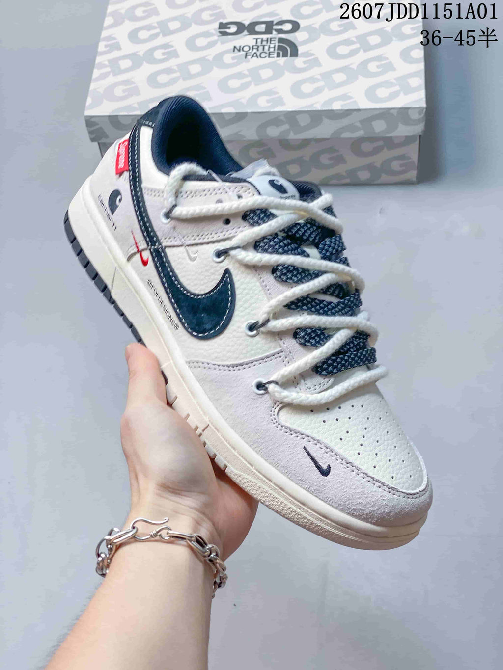 Angled side view of an off-white and navy low-top sneaker with red accent details