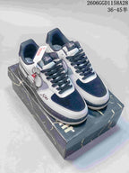 Pair of white, grey, and navy low-top sneakers with layered Swoosh details, shown on a patterned box.