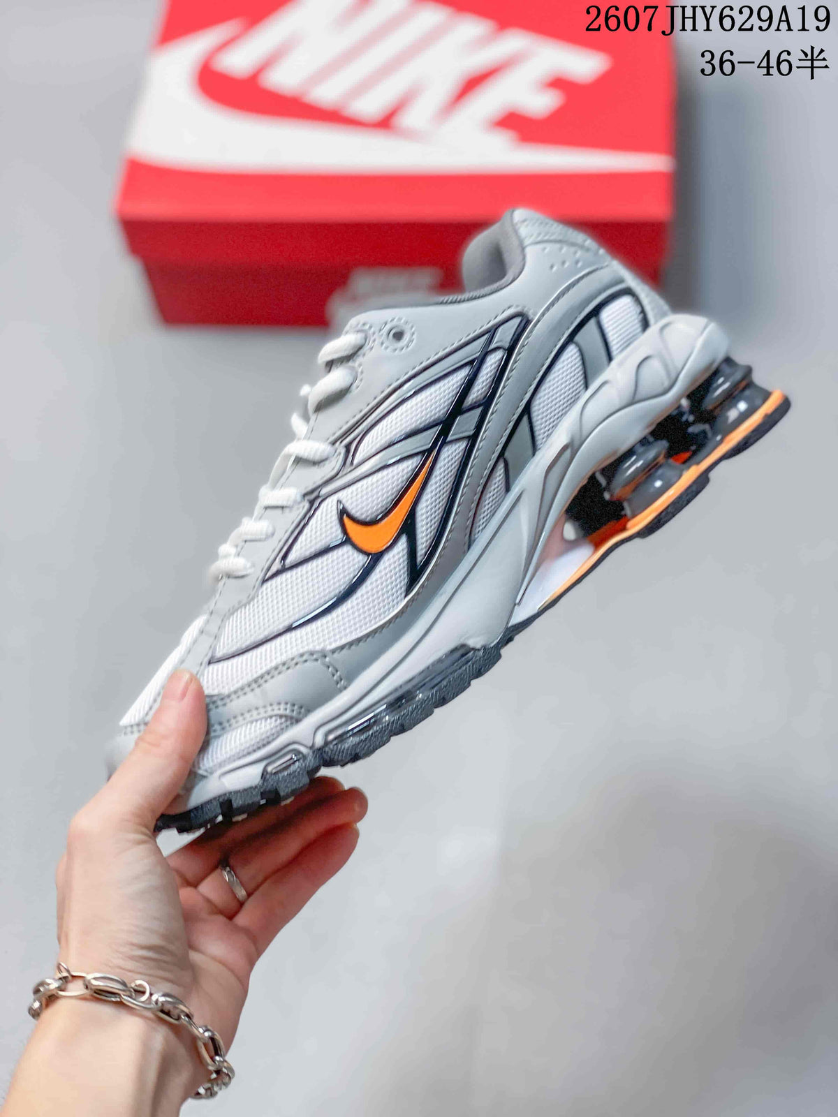 Side profile highlighting the layered grey and white upper, orange Swoosh detail and columned heel.