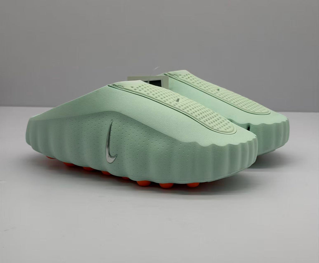 Front three-quarter product view highlighting the slip-on shape, perforated upper, side branding, and orange outsole elements.