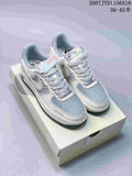 Pair of light grey and white low-top sneakers with blue-grey panels, patterned sides and a dark outsole, shown on a shoebox.