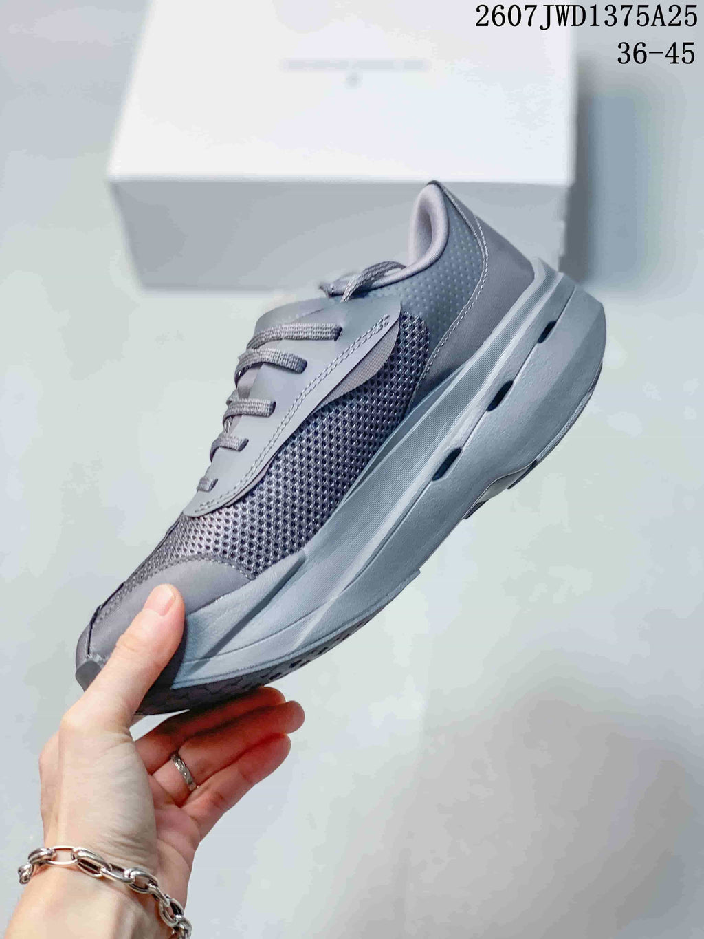 Side view of the gray sneaker showing mesh panels, layered overlays, laces, and the sculpted gray sole.