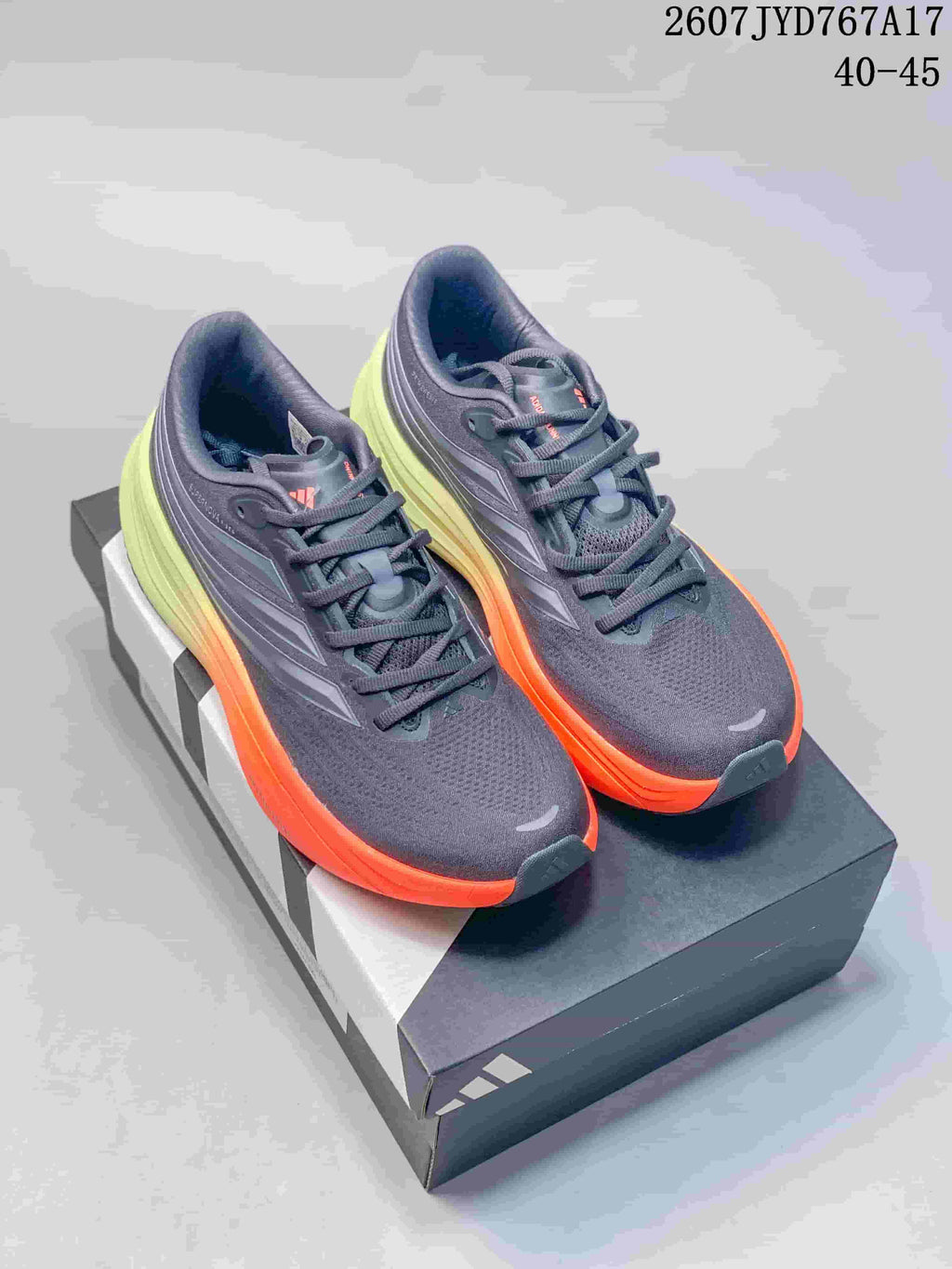 Pair of dark gray Adidas sneakers with bright orange midsoles and lime-green heel sections.