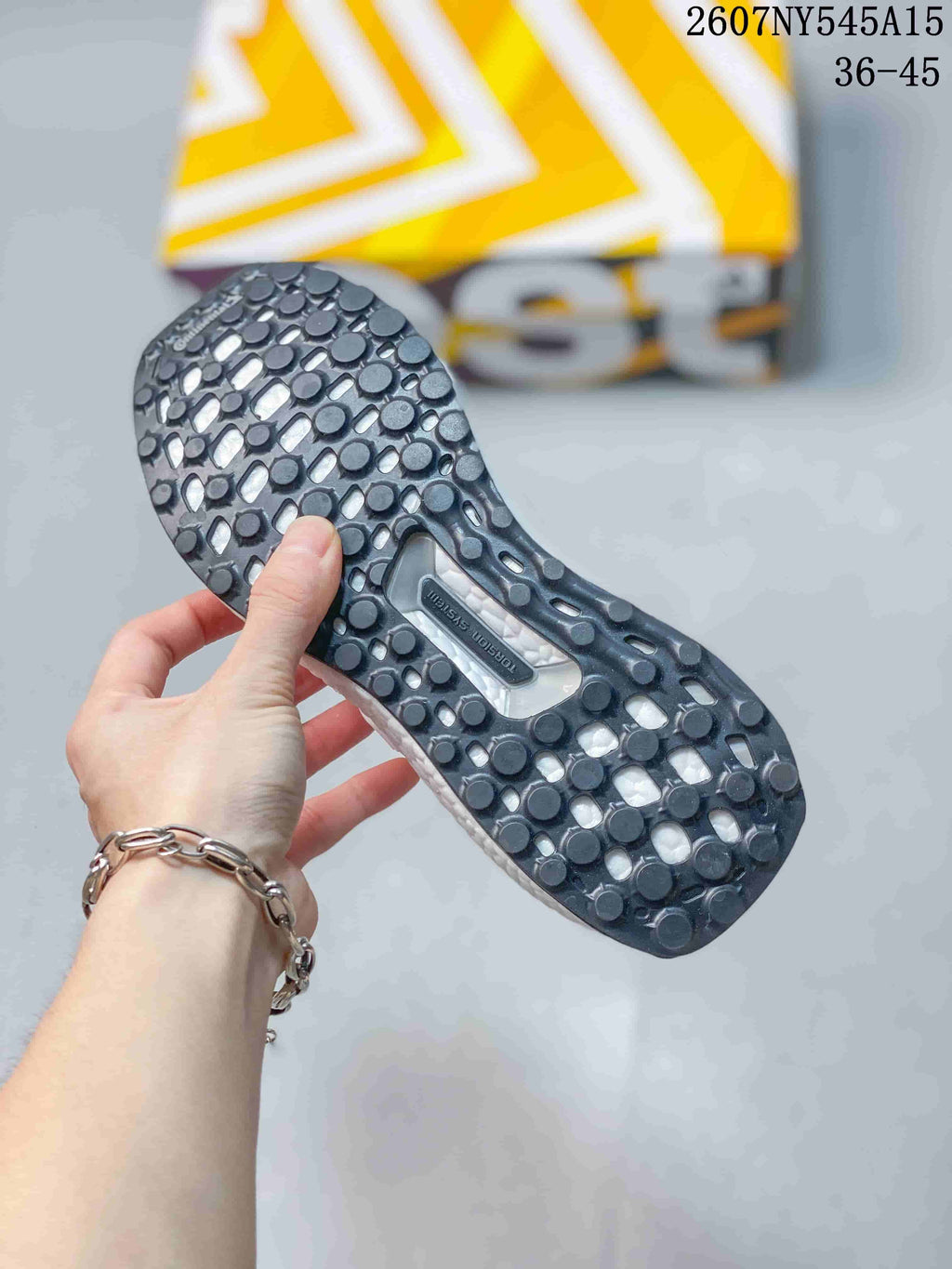 Close view of the dark patterned outsole on a white Adidas Ultraboost Light sneaker, with model code 2607NY545A15 and size range 36–45 visible above.