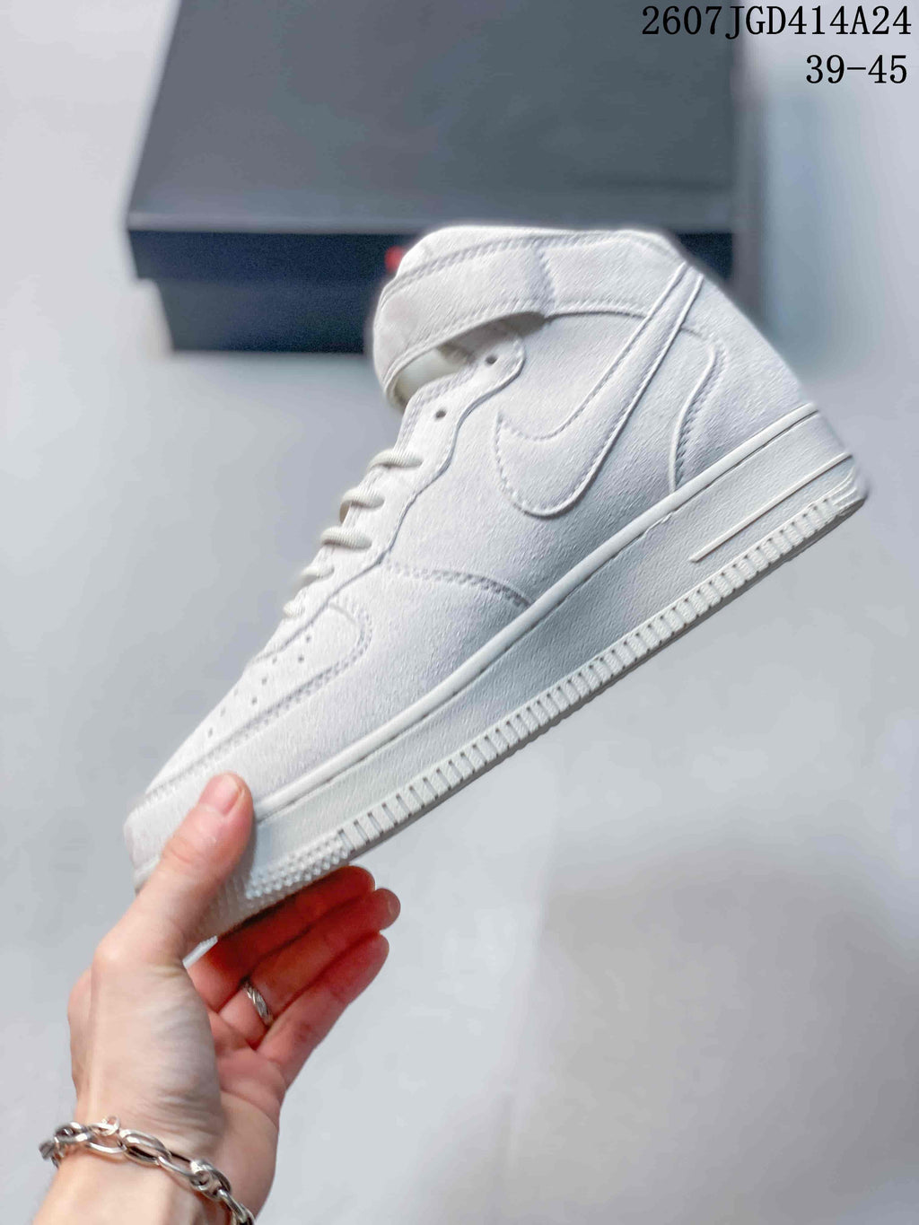 Side view of a white mid-top sneaker showing the Swoosh panel, ankle strap, layered upper, and textured sole edge.