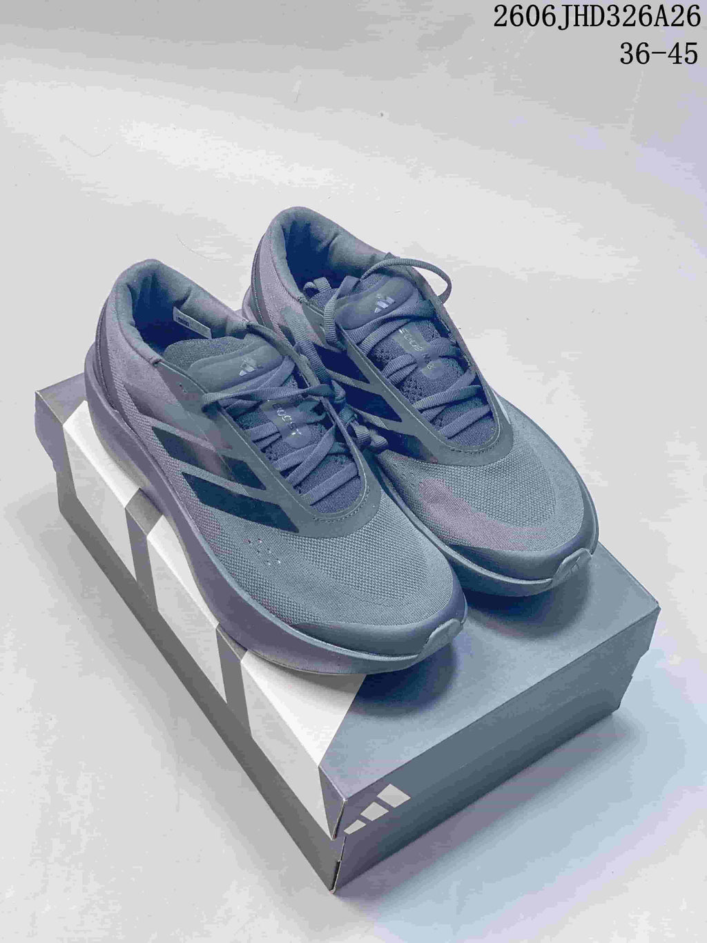 Pair of charcoal adidas Supernova Rise 3 running shoes displayed on a shoe box