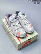 Pair of white and light gray low-top sneakers with gray Swooshes and orange accents, shown on a branded shoe box.
