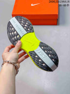 Close-up of the sneaker outsole showing black textured rubber sections, a pale blue central section, and a bright lime midfoot area.