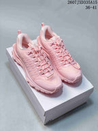 Pair of pink Alo Yoga sneakers displayed on a shoebox, showing the layered upper and low-top profile.