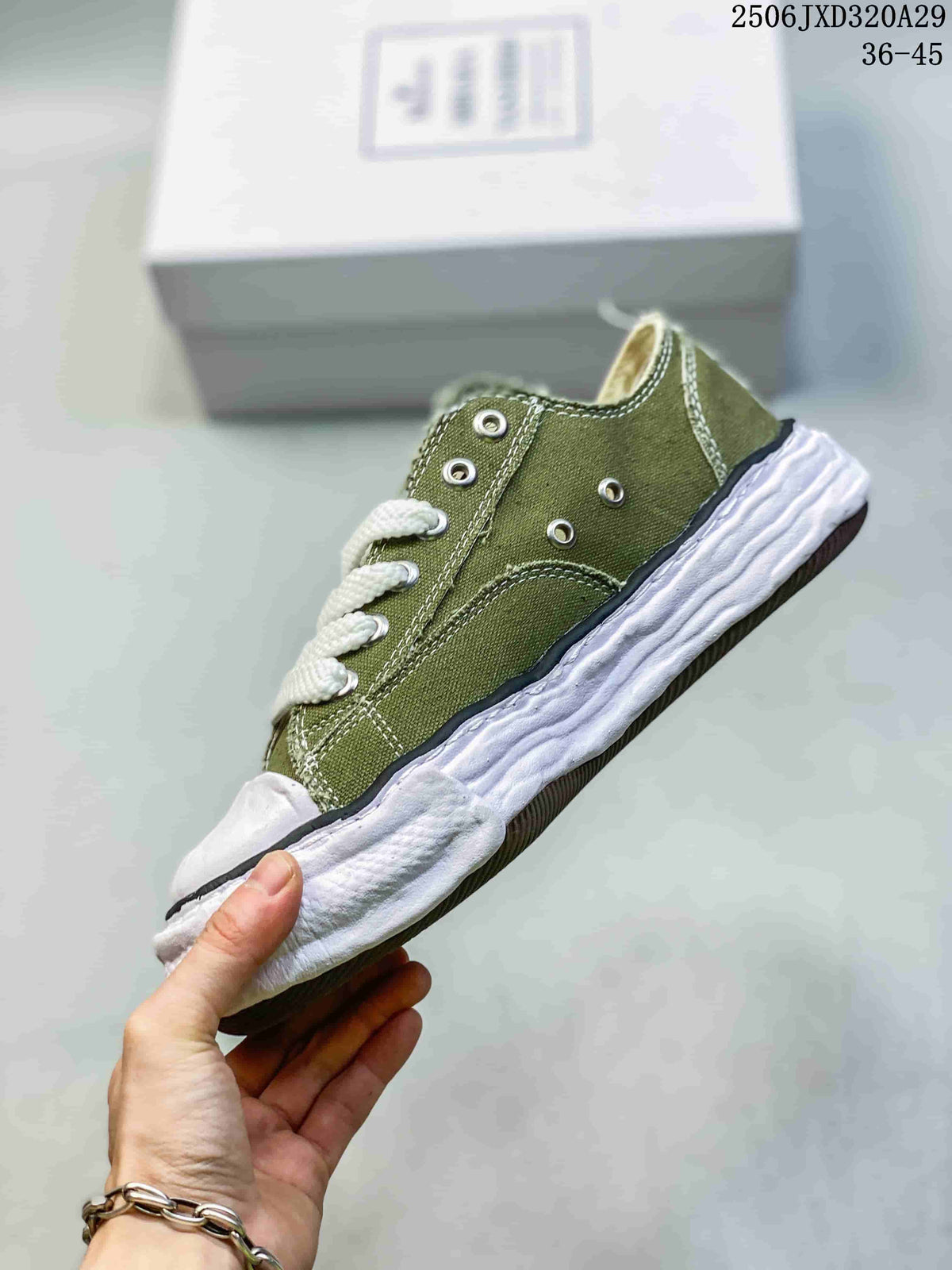 Side view of an olive low-top sneaker showing contrast stitching, metal eyelets, dark trim, and a sculpted white outsole.