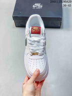 Top view of the sneaker showing white laces, perforated toe box, red patterned tongue label, and gold-tone lace accessory.