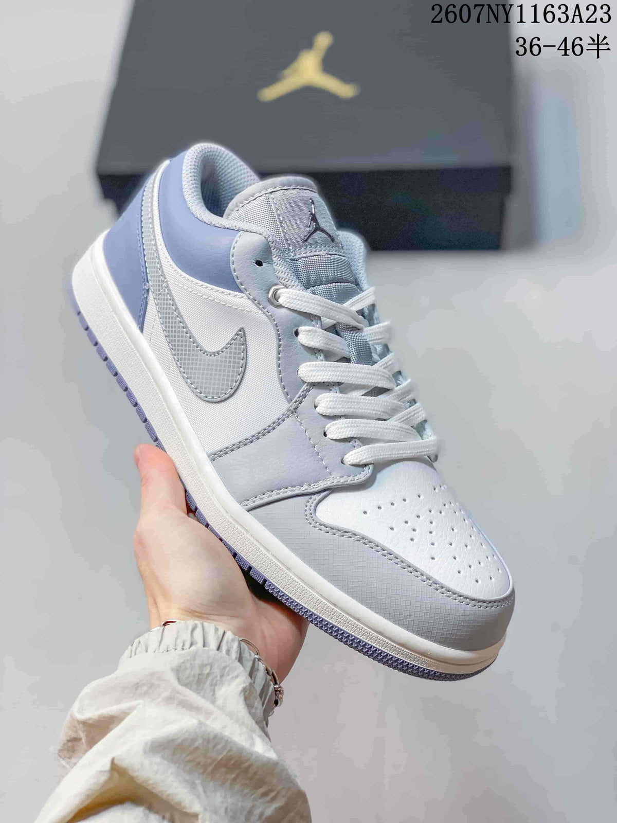 Angled side view showing the light grey and white upper, side panel, white midsole, and patterned outsole.
