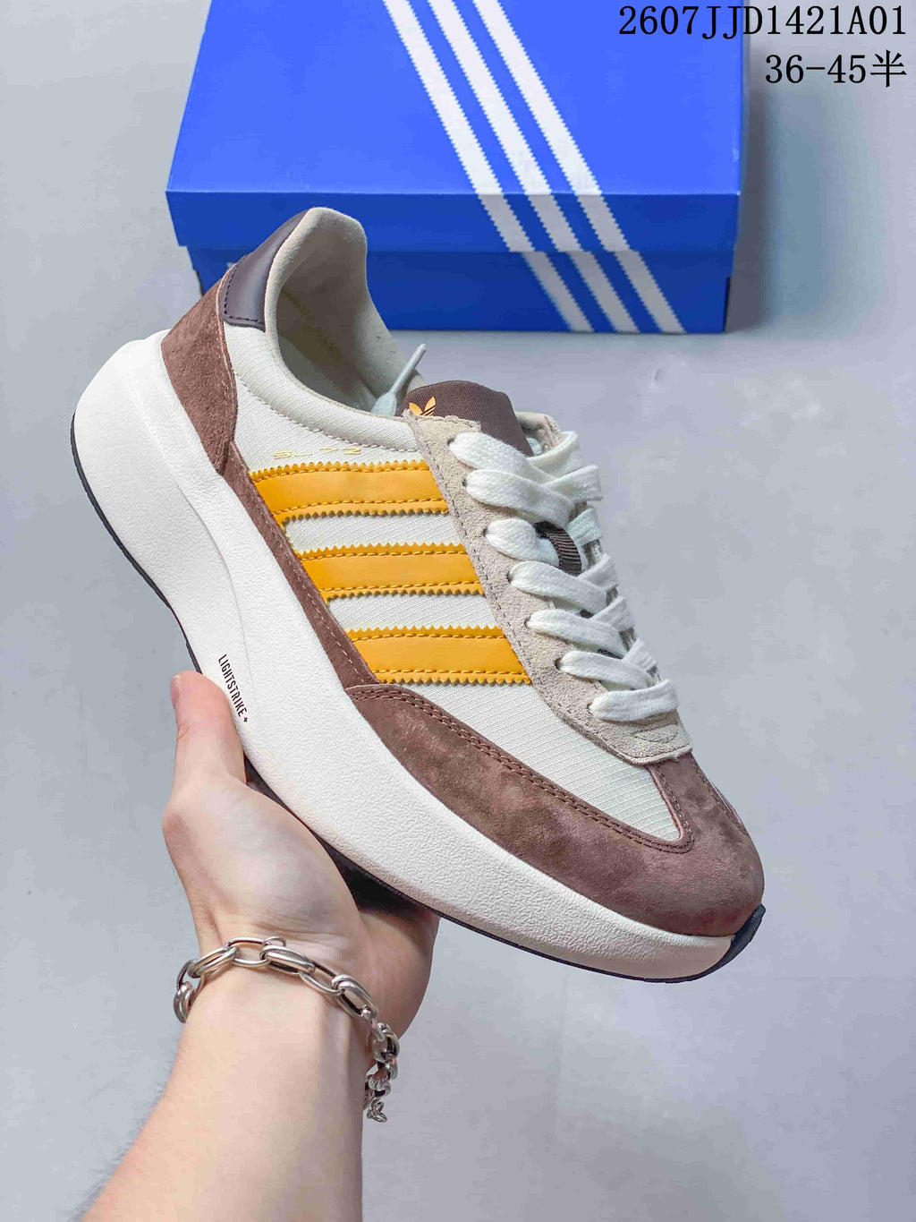 Angled side view of the off-white and taupe sneaker with yellow stripes