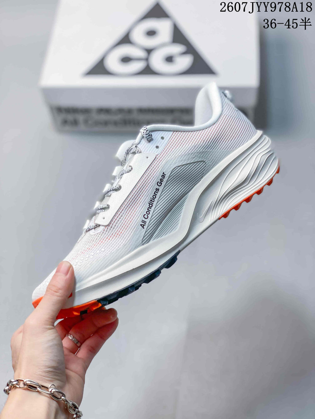 Side view of a Nike ACG Pegasus Trail shoe showing the light upper, dark side graphic, sculpted midsole, and orange outsole lugs.