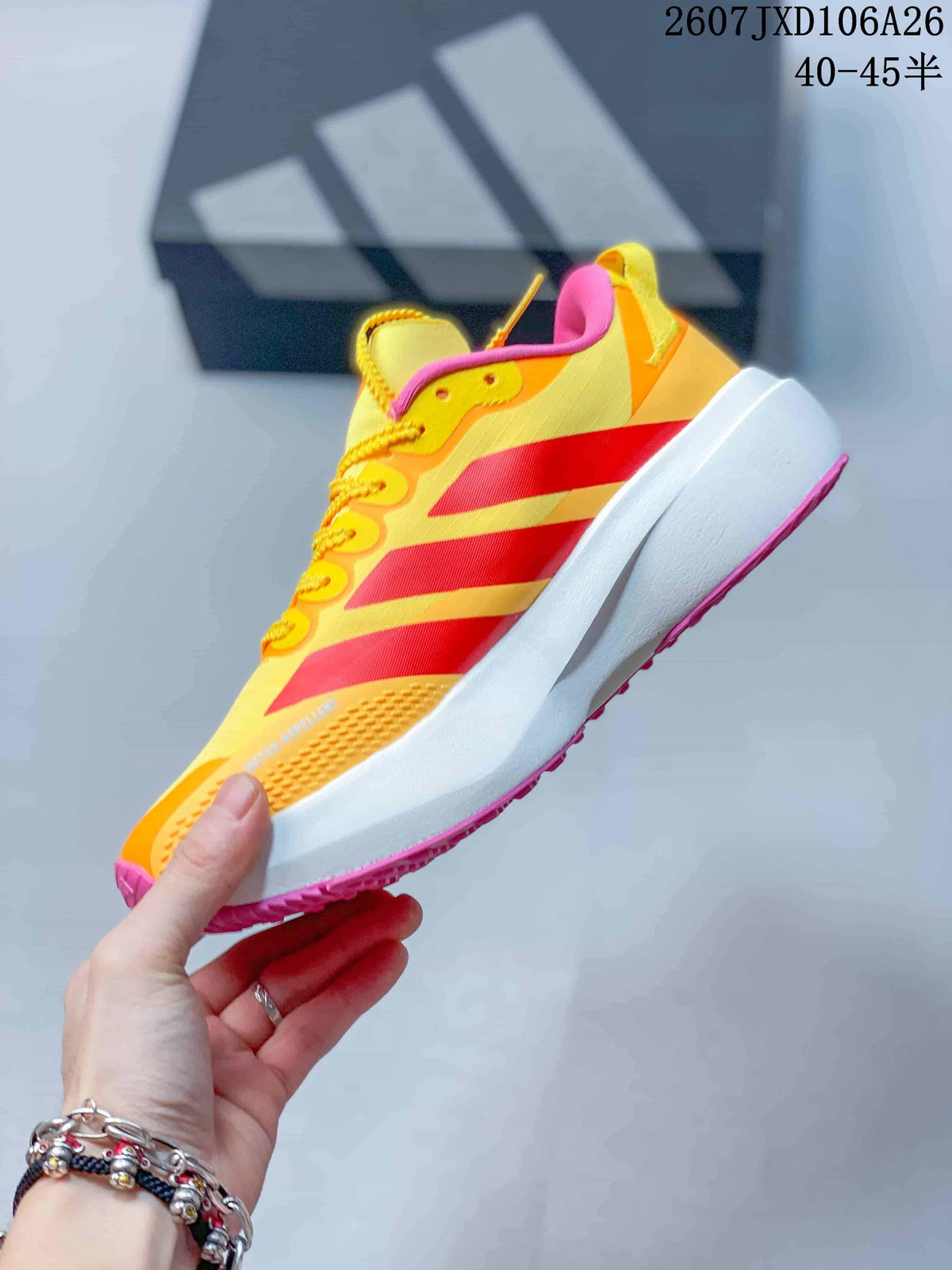 Side view showing the yellow upper, red side stripes, white midsole and pink outsole.