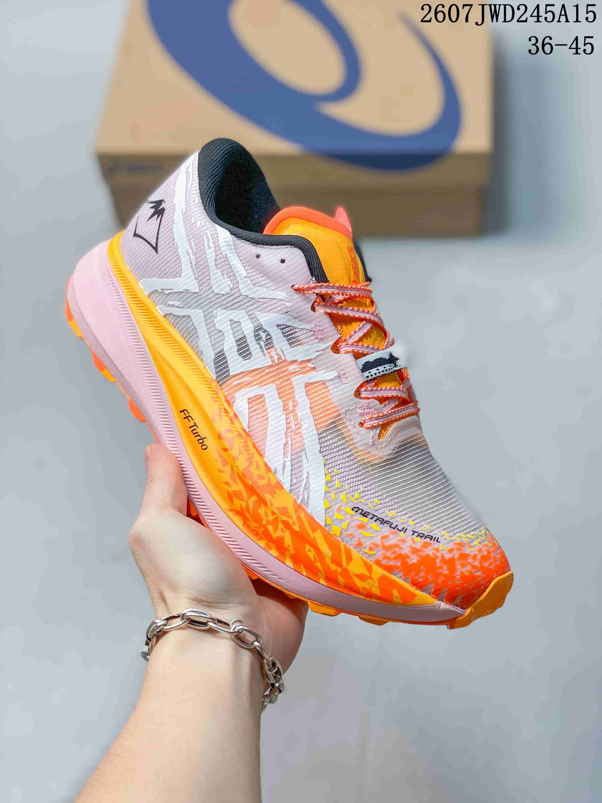 Close-up of a white, orange and pink ASICS sneaker with patterned upper and orange outsole accents.