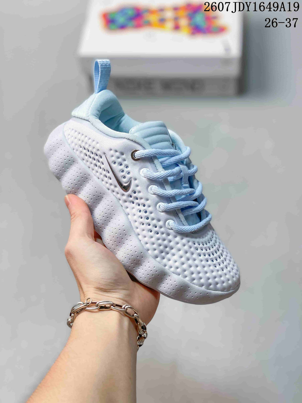 White Nike Mind 002 kids sneaker shown from a three-quarter angle with perforated details.