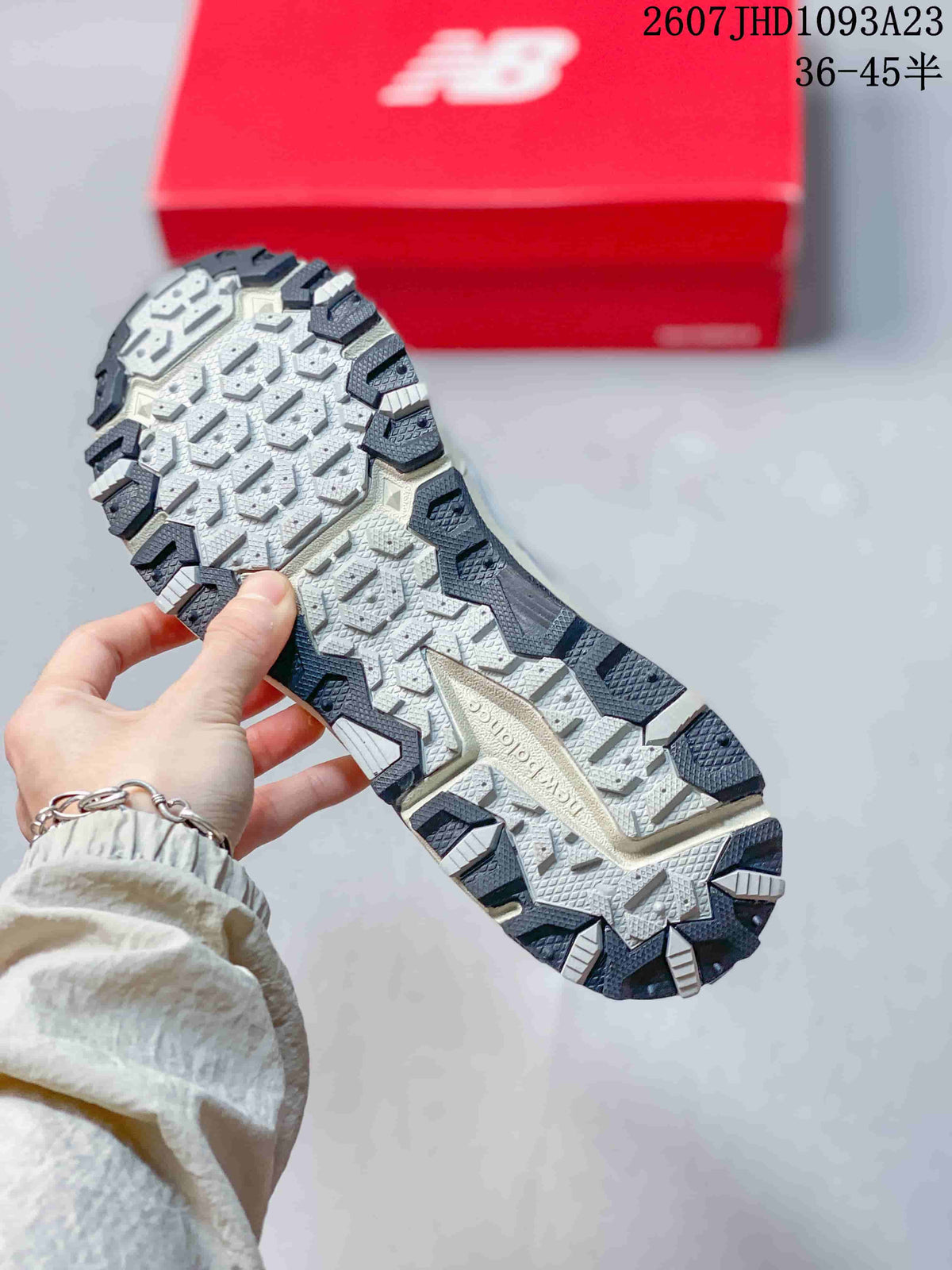 Close view of the patterned outsole with dark and light traction sections on a grey sneaker.