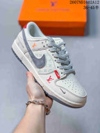 Angled side view showing the white and gray upper, red accent details, patterned side panel, gray Swoosh, and low-top construction.
