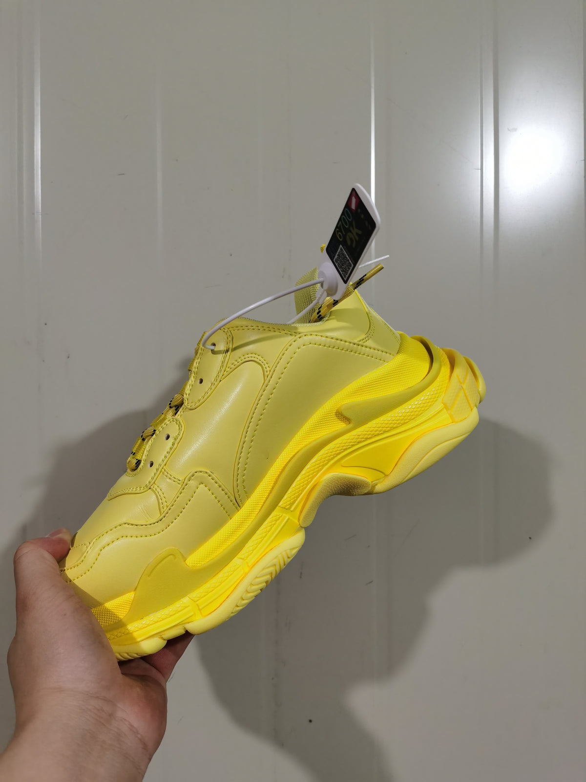 Side and outsole view of a yellow Balenciaga Triple S sneaker showing layered panels, tonal stitching and a sculpted sole.