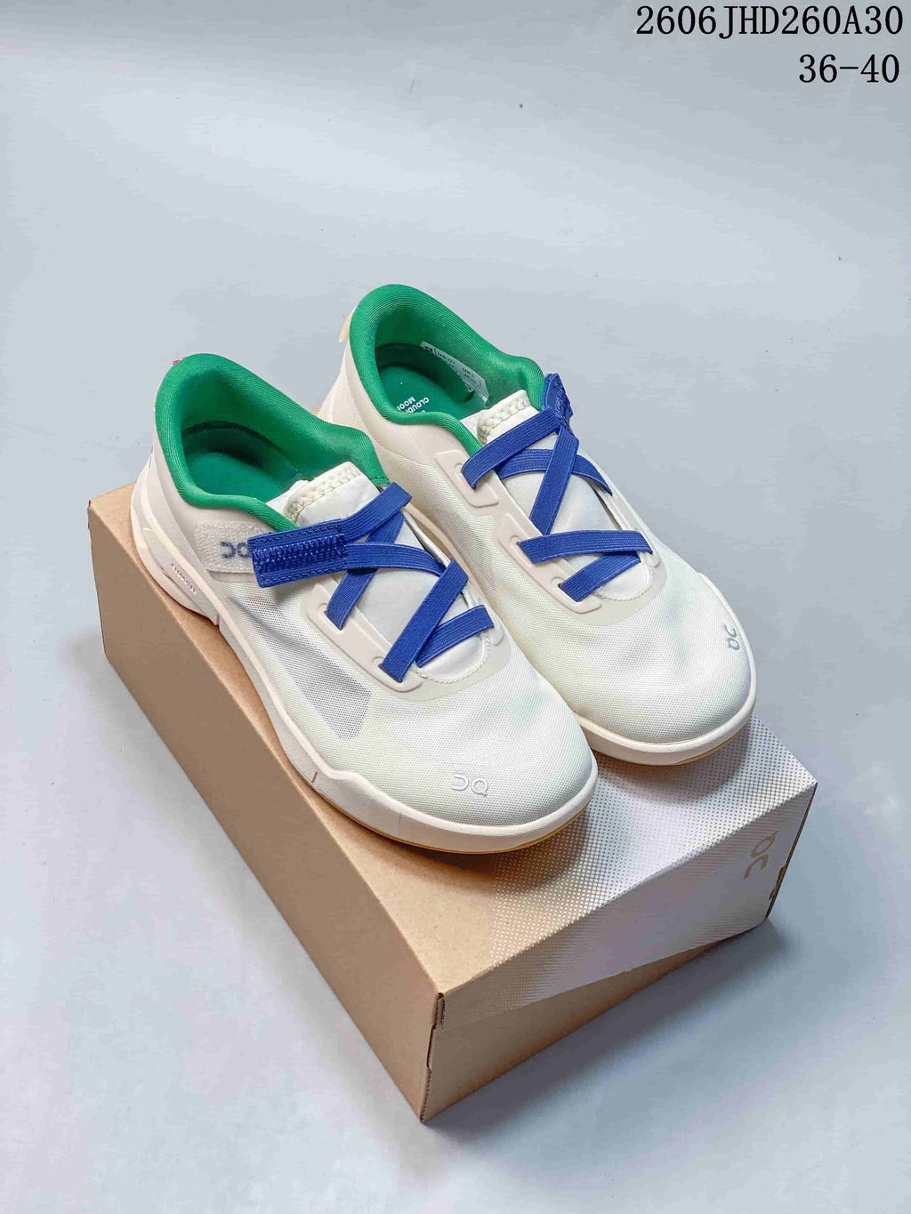 Off-white On Cloudnova Moon sneakers with blue laces and green lining, displayed on a shoebox.