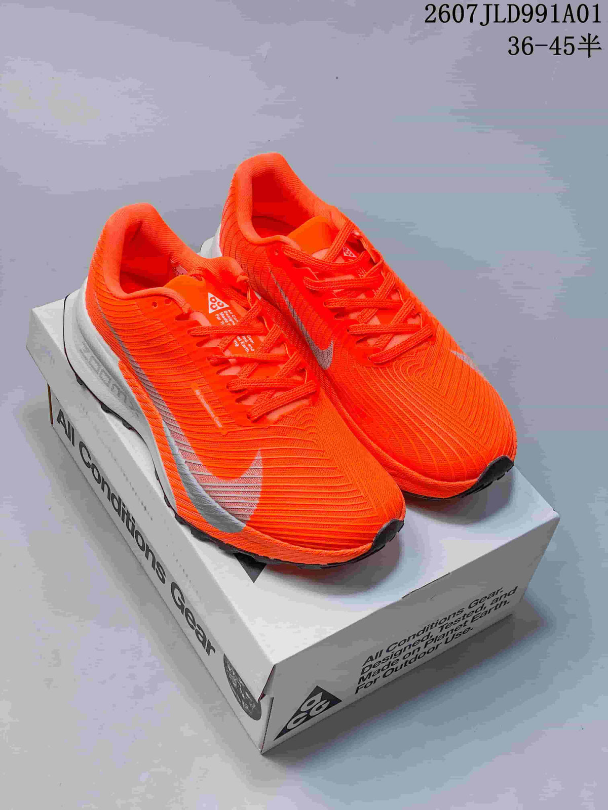 Pair of bright orange Nike ACG trail shoes with light-colored accents