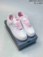 Pair of white Nike Air Force 1 sneakers with pink ribbon laces and pink collar details displayed on a shoe box.