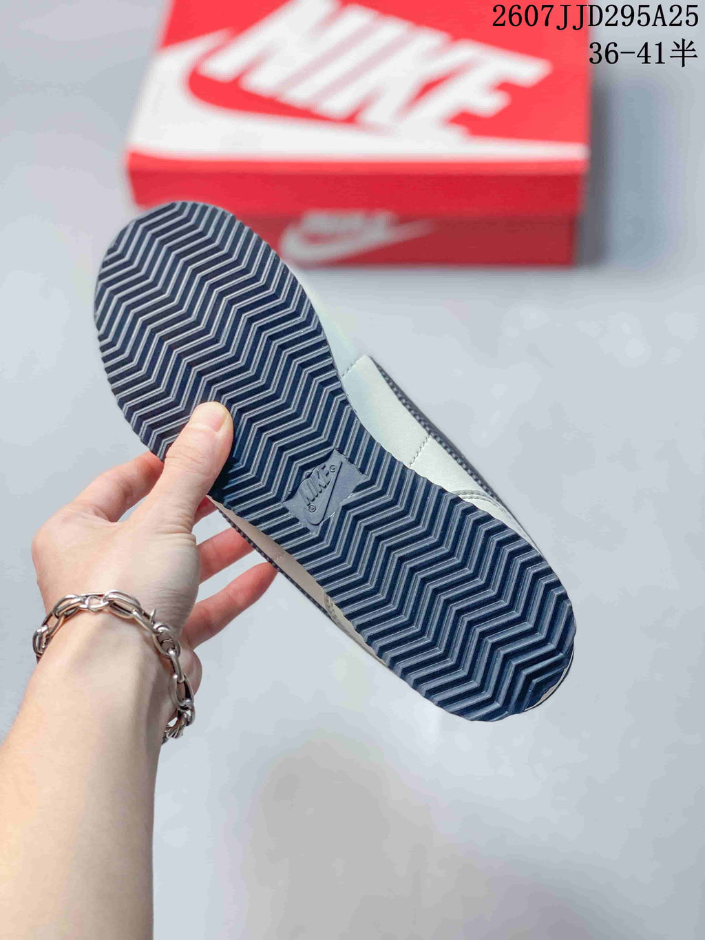 Underside view showing the sneakers' dark patterned rubber outsole with zigzag traction lines.