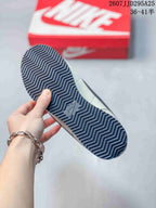 Underside view showing the sneakers' dark patterned rubber outsole with zigzag traction lines.