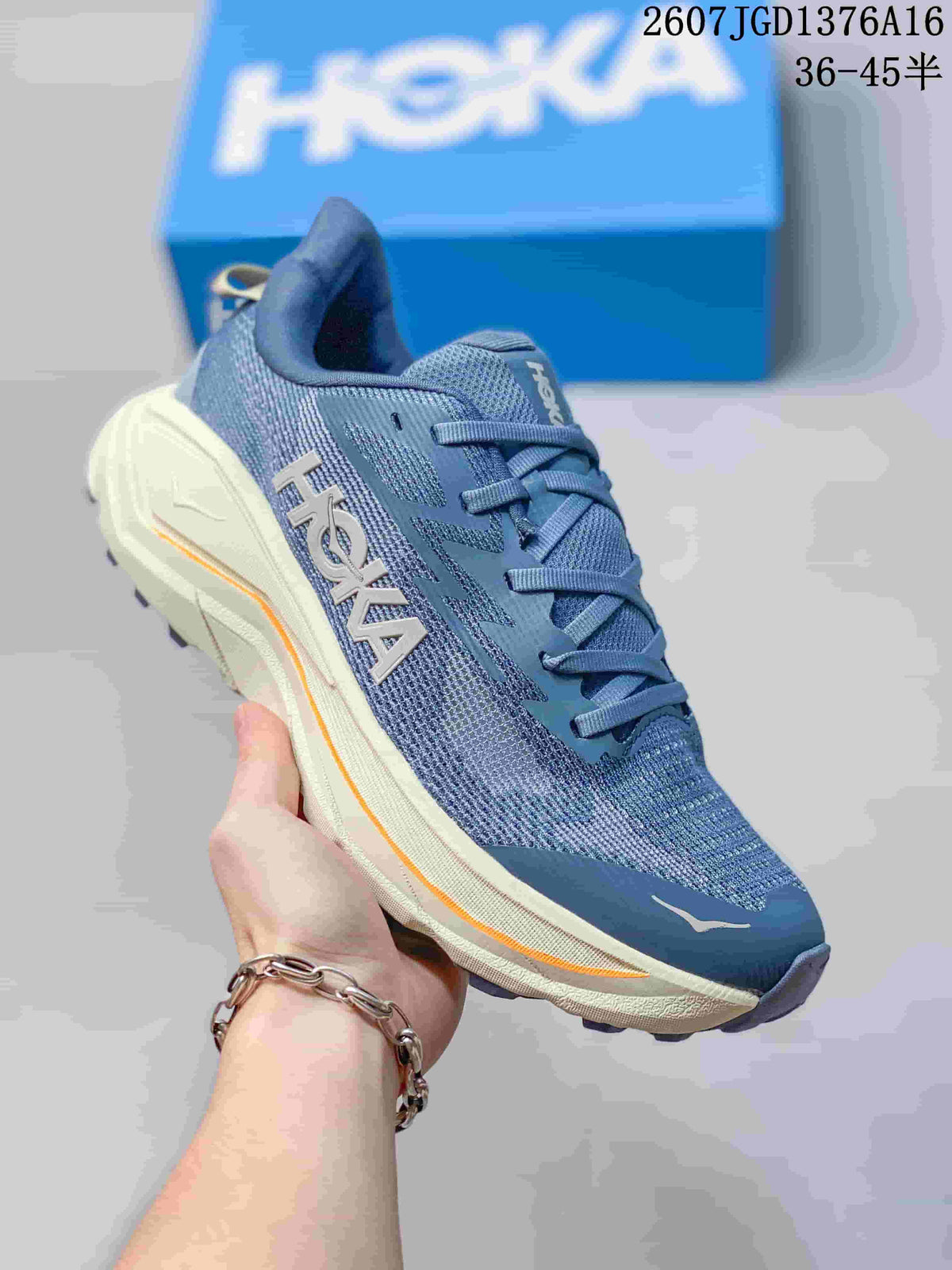 Angled side view of the blue HOKA shoe showing the branded side detail, cream midsole and orange accent.