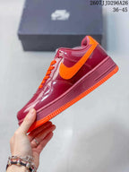 Side view highlighting the glossy burgundy upper, orange Swoosh, burgundy midsole, and orange outsole.