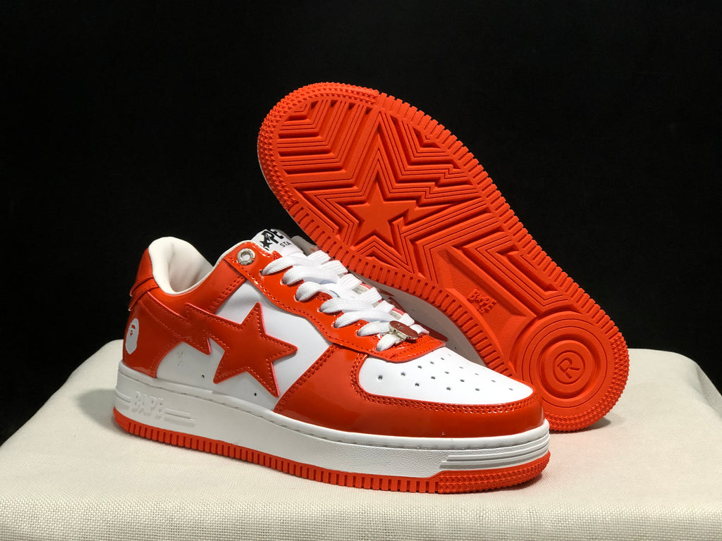 Angled view of the sneakers with one shoe lifted to show the orange patterned outsole and star detail.
