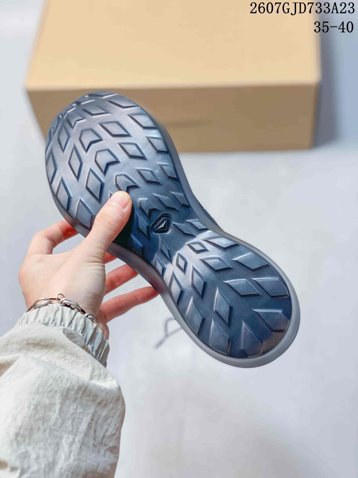 Close view of the sneaker outsole showing a dark geometric tread pattern and central logo detail.