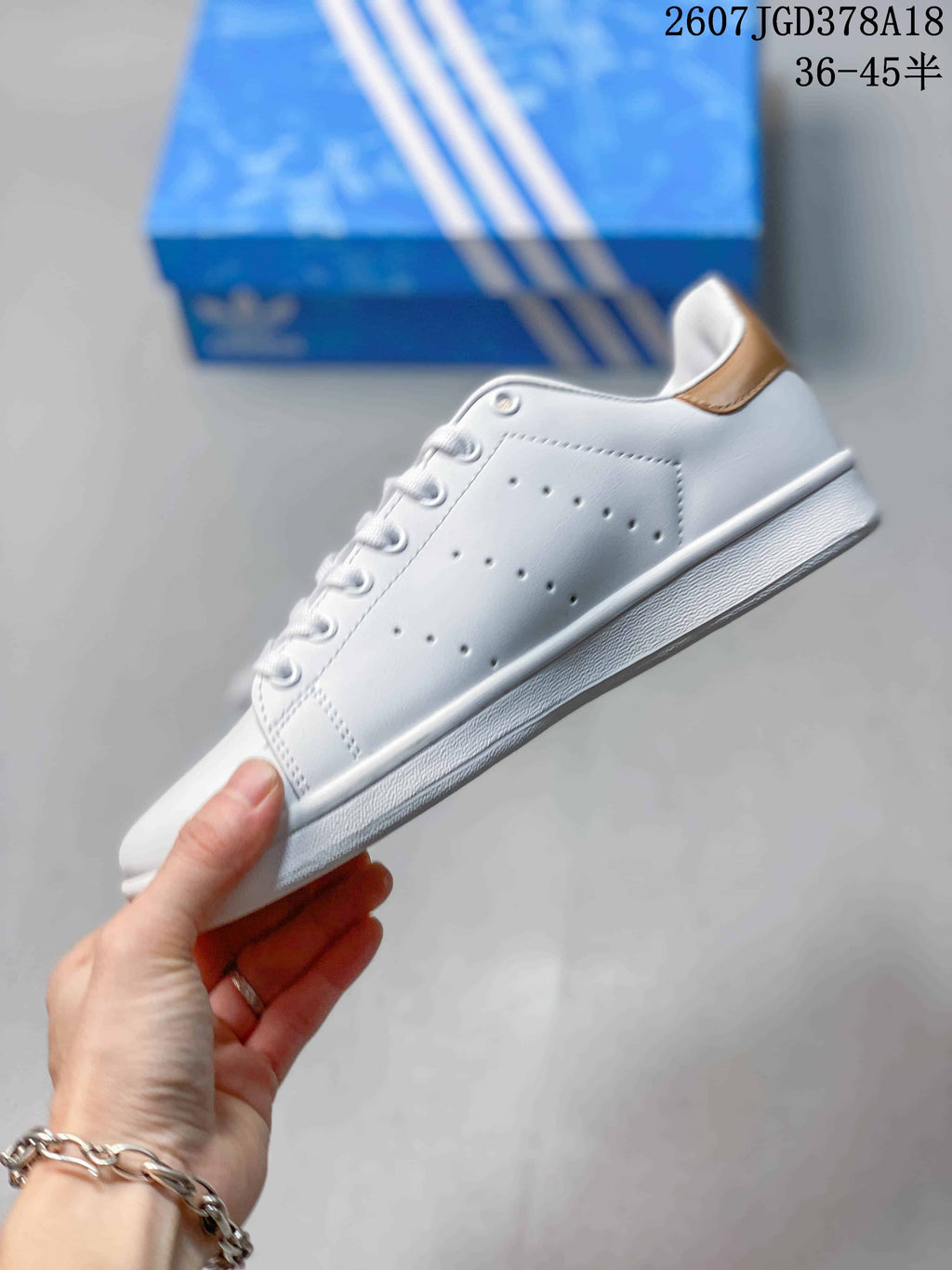 Side profile showing the white upper, perforated stripe detail, gold heel accent and textured sole.