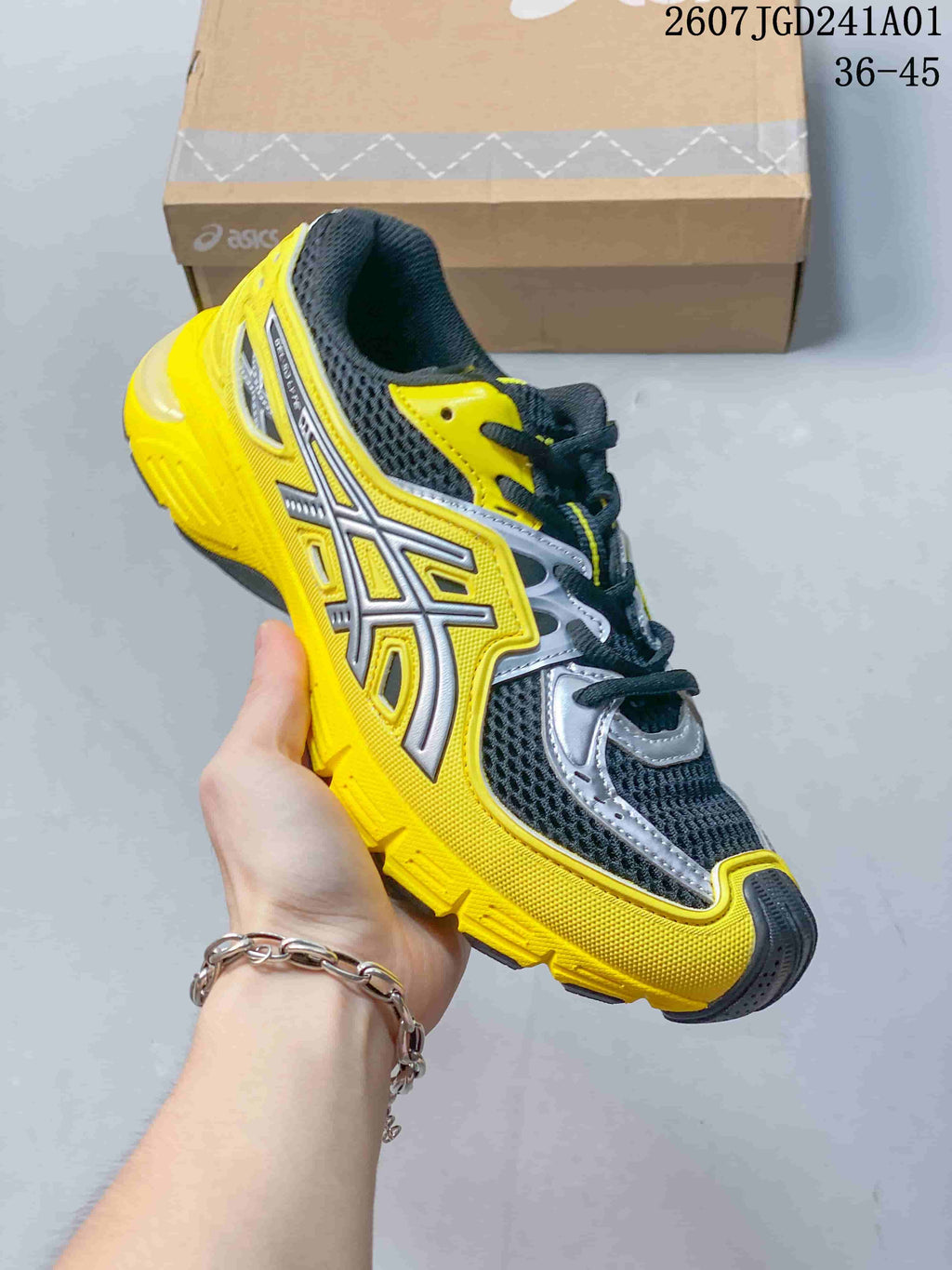 Angled side view of the yellow, charcoal, and silver ASICS sneaker.