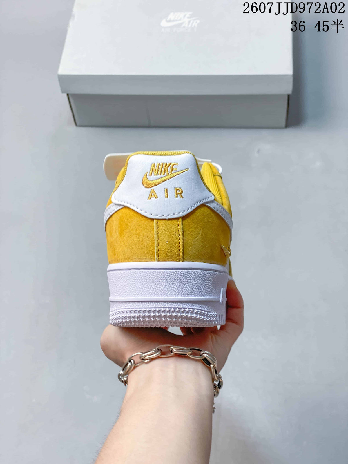 Rear view of a yellow and white Nike Air Force 1 low-top sneaker with embroidered heel branding.