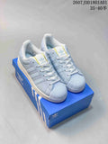 Light blue Adidas Originals Superstar sneakers shown on a blue box