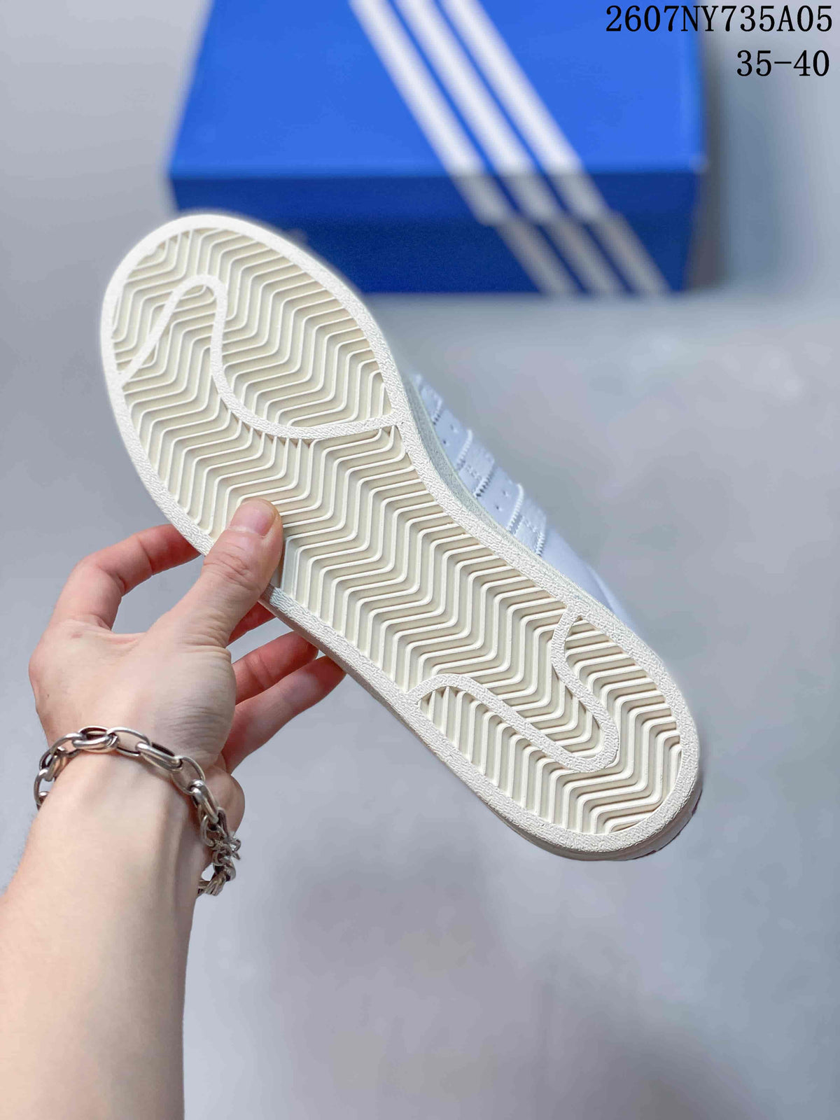 Underside of a white sneaker showing a cream zigzag rubber outsole pattern.