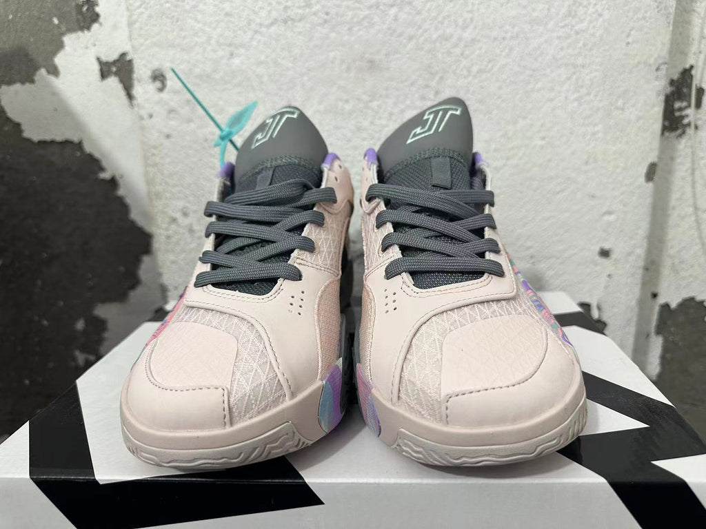Front view of pale pink and gray basketball shoes with dark laces, patterned toe panels, and purple collar trim.
