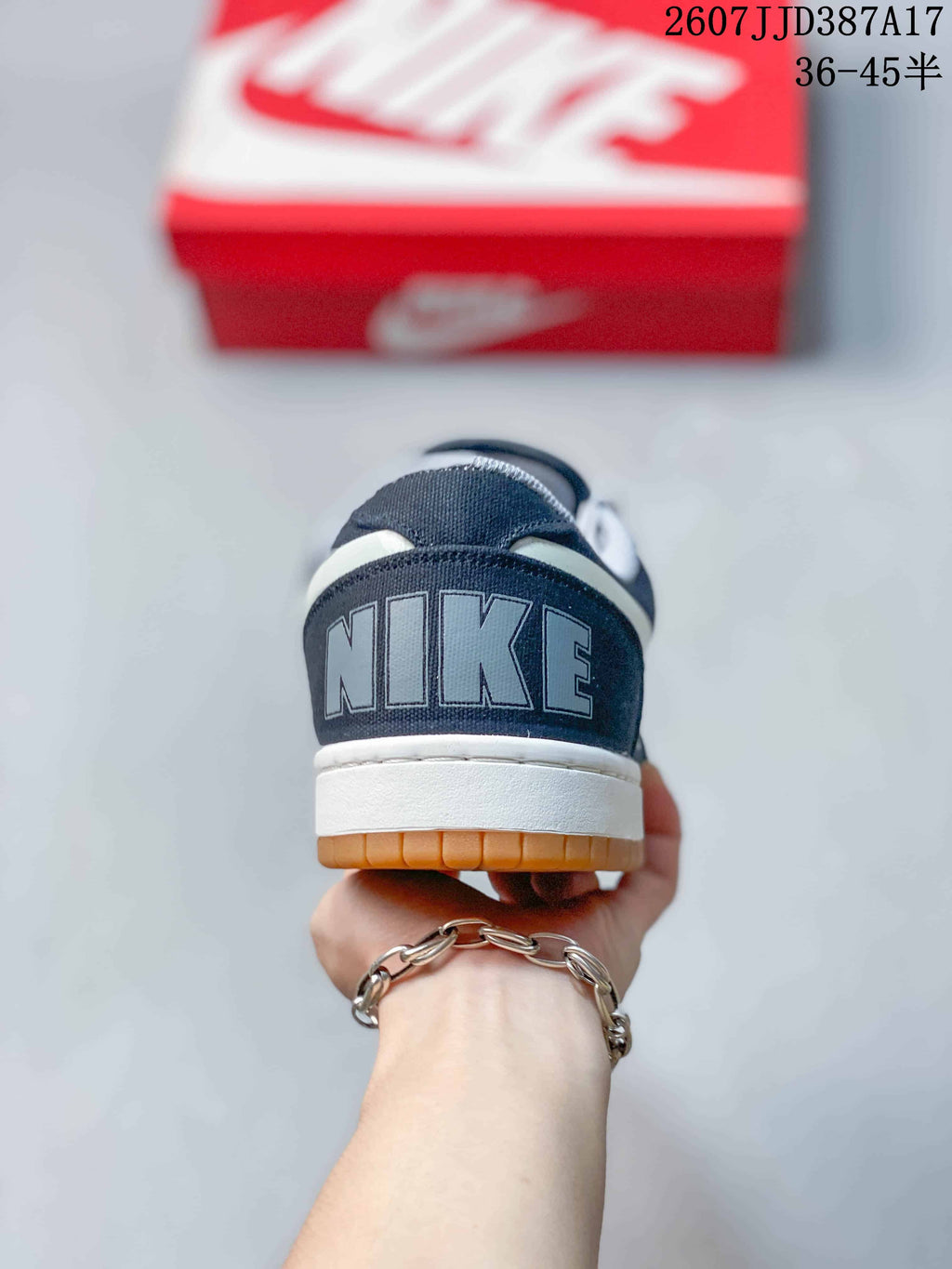 Rear view of the navy sneaker showing large Nike lettering on the heel, a white midsole, and gum outsole.