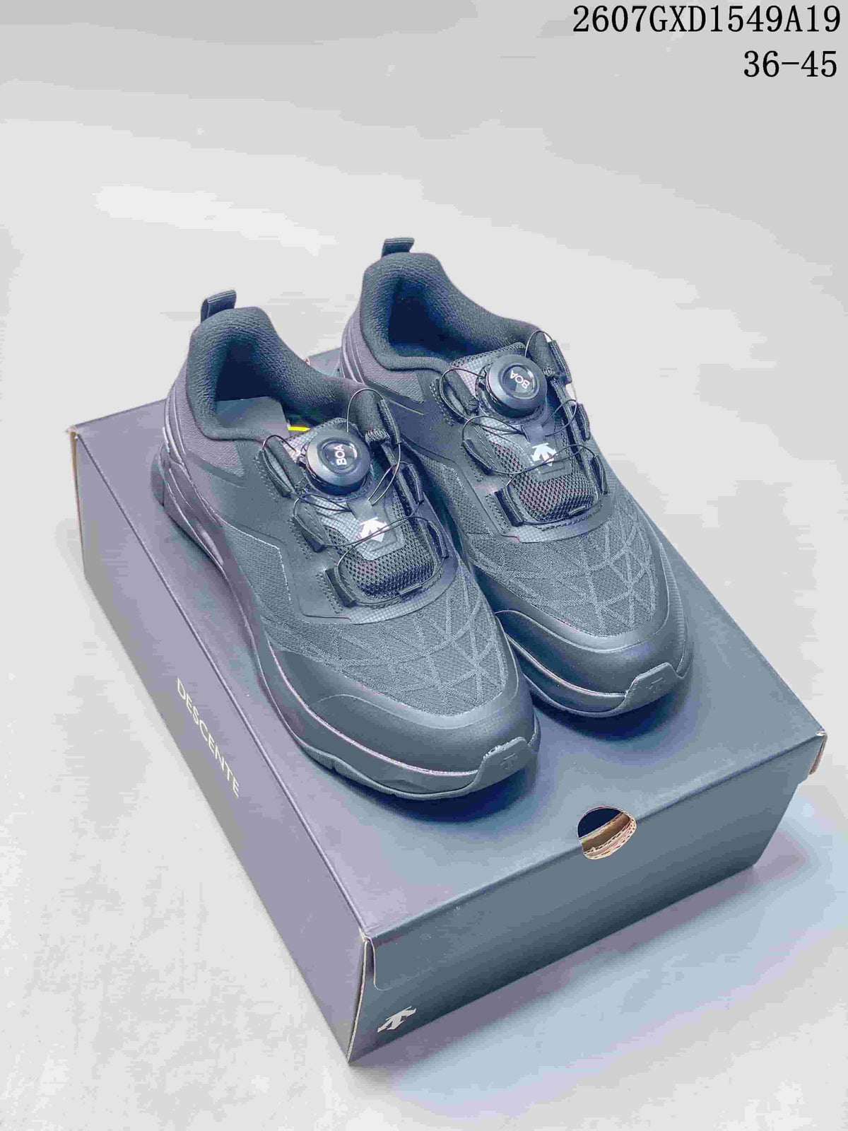 Pair of black DESCENTE Circuit 2.0 Wire sneakers displayed on a shoebox, with the dial closures visible.