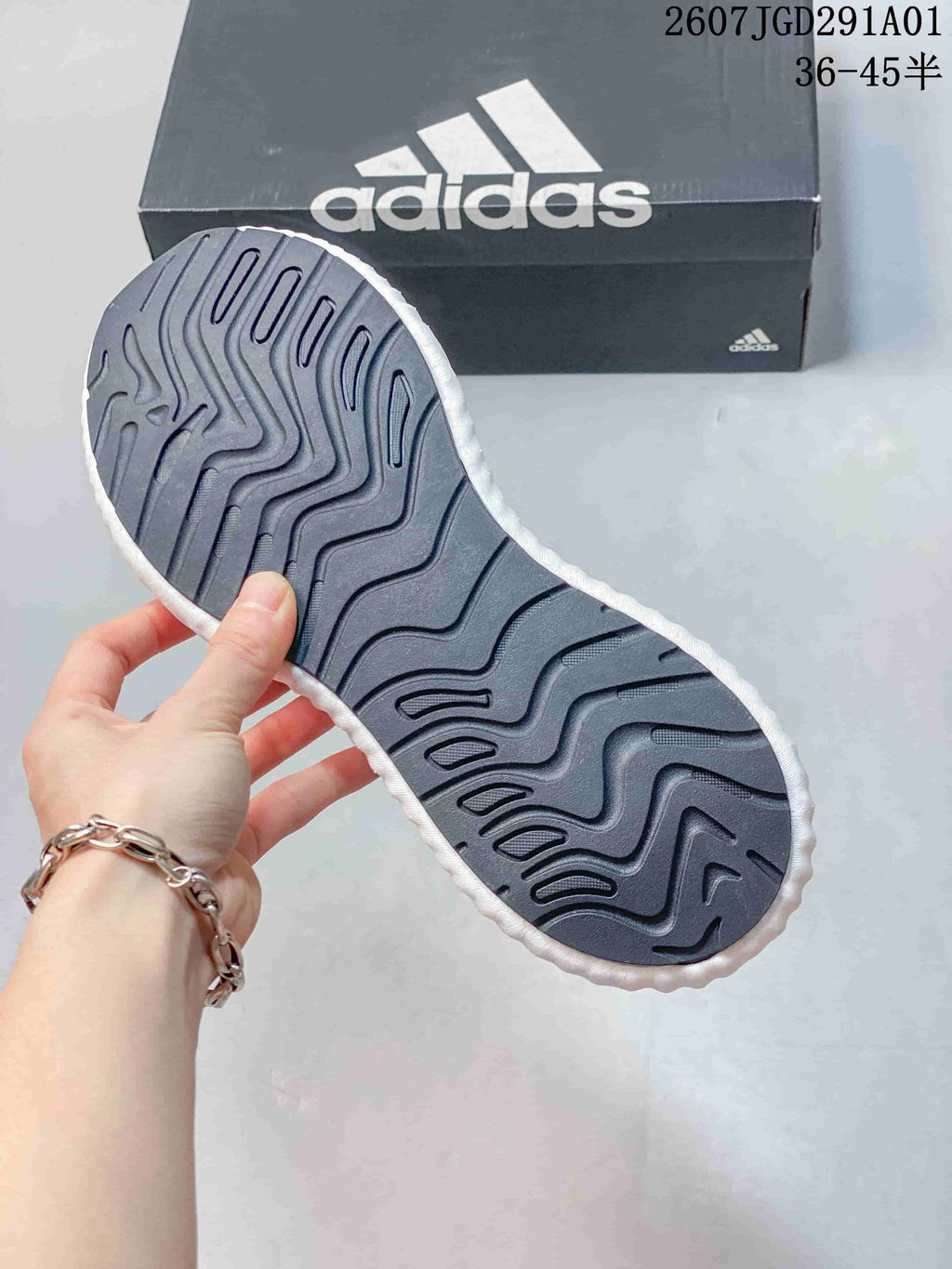 Underside of a sneaker showing a dark patterned outsole and white midsole edge.