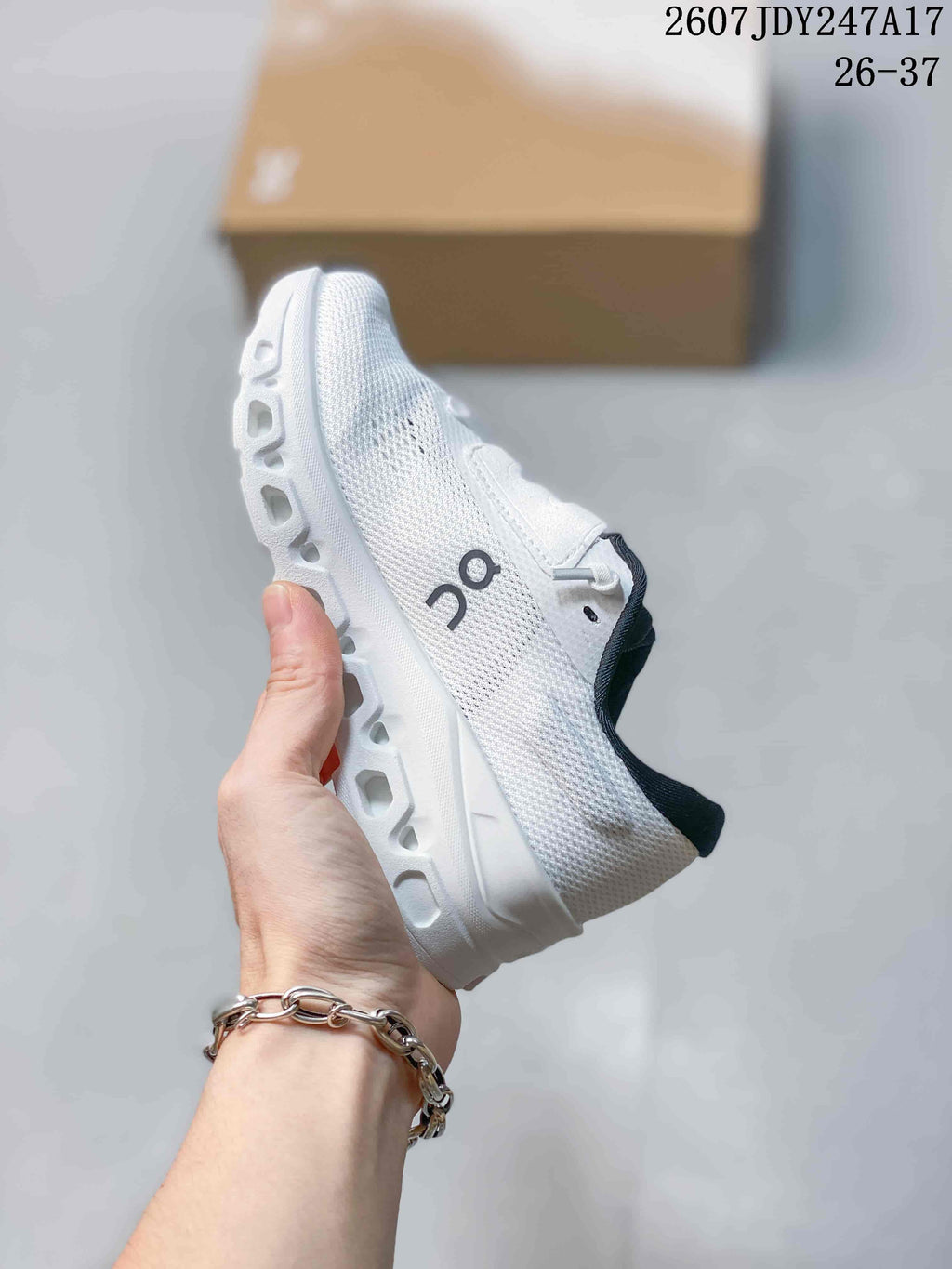 Side view of the white sneaker showing the mesh-like upper, side logo, laces, and segmented midsole.