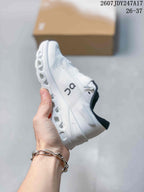 Side view of the white sneaker showing the mesh-like upper, side logo, laces, and segmented midsole.