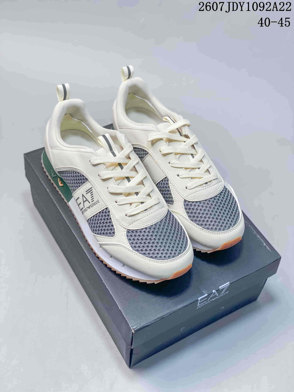 Cream-colored EA7 low-top sneakers with dark textured panels, white laces and contrasting outsole details.