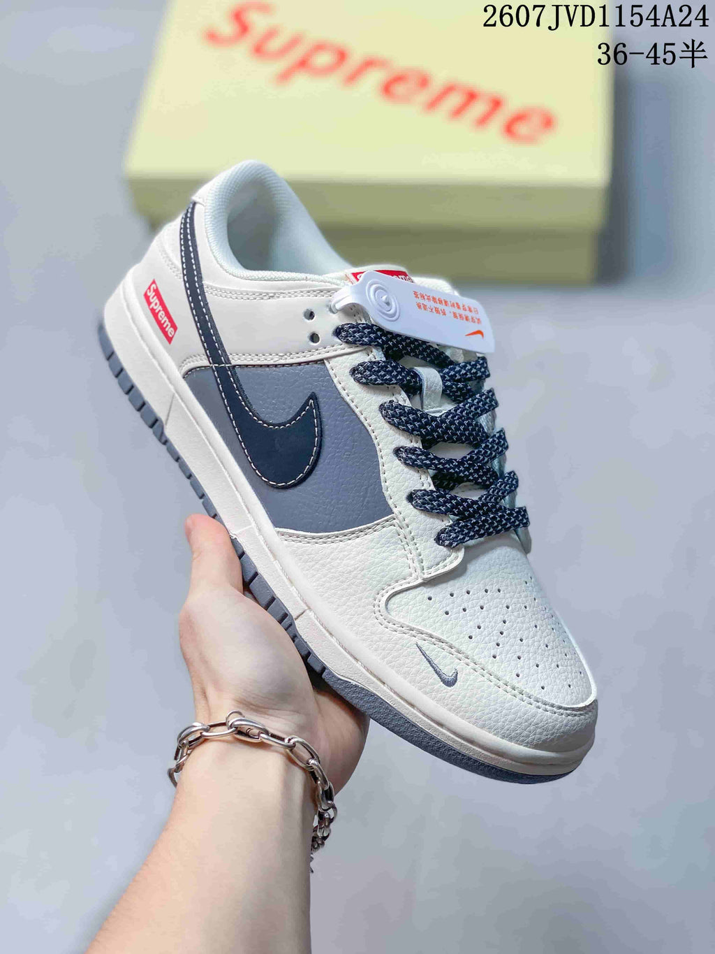 Angled side view of the white and navy low-top sneaker with Supreme heel branding.