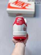 Rear view of the white sneaker with a red heel tab, red outsole edge, and illustrated side detail.