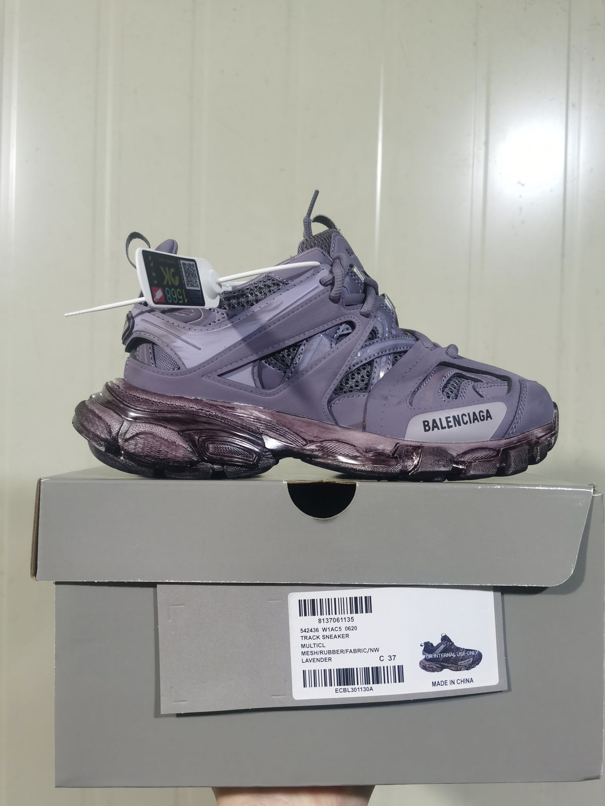 Lavender Balenciaga Track sneaker displayed on a shoebox, showing the side profile, layered panels, mesh sections, dark sculpted outsole, and box label.