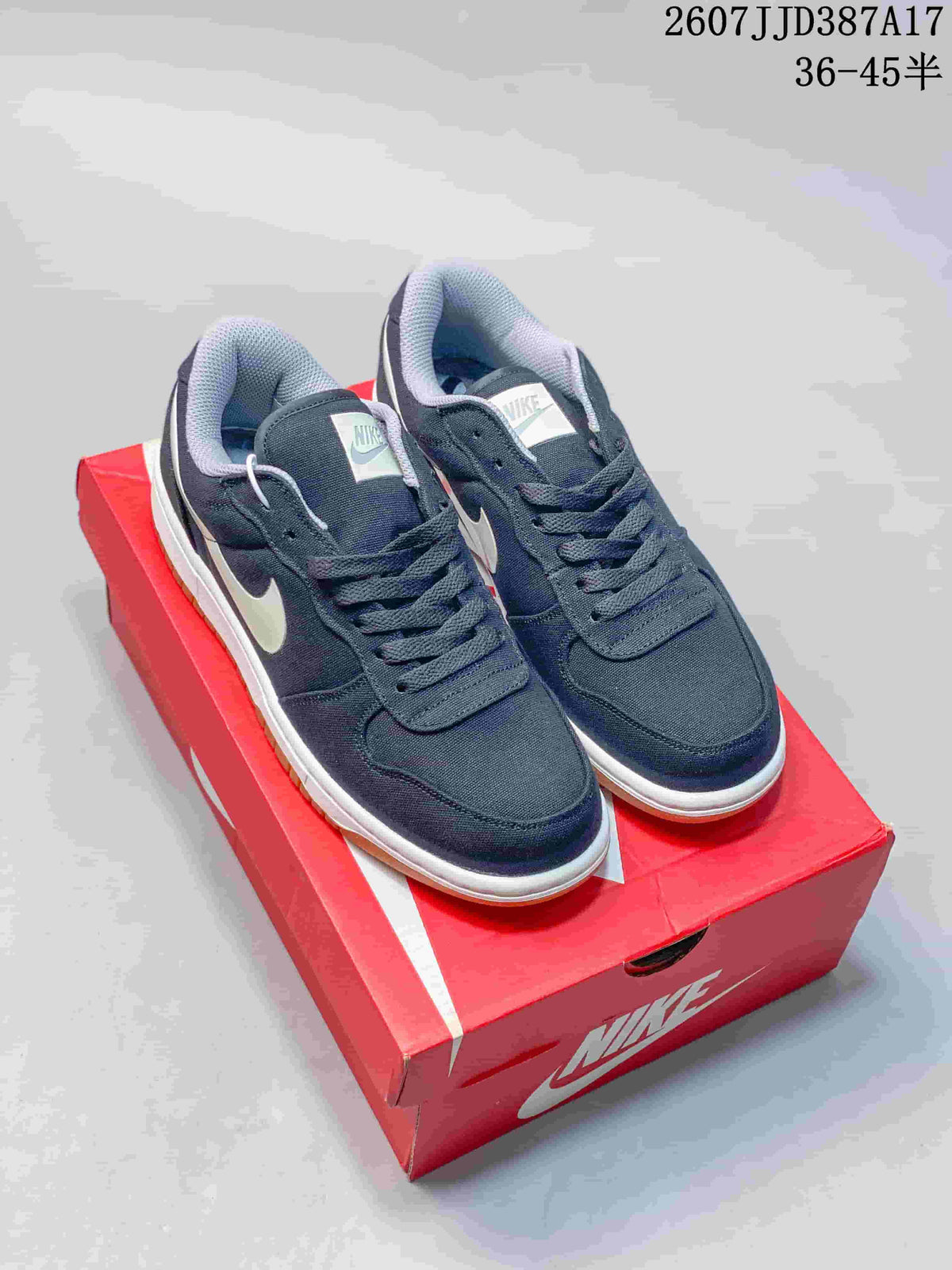 Pair of navy Nike low-top sneakers displayed on a red Nike shoebox, showing white Swoosh branding, white midsoles, and gum outsoles.