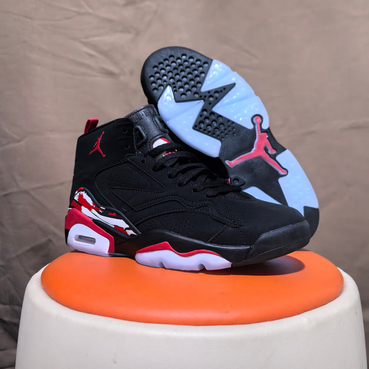 Black and red high-top sneaker with outsole visible beside it